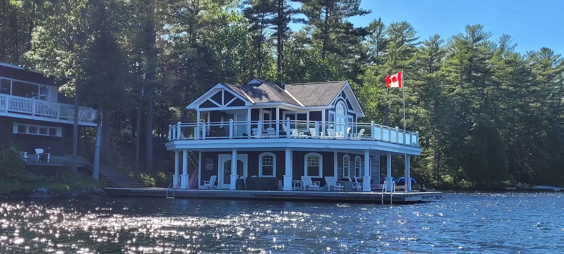 Two-storey navy and white boathouse on a Muskoka lake, freshly painted